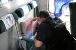 Funkcjonariusz KAS w przedziale pociągu podczas wykrycia papierosów