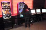 Funkcjonariusz KAS w nielegalnym salonie gier hazardowych. W tle widoczne automaty i komputery