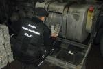 Funkcjonariusz KAS wyjmuje papierosy ze zbiornika paliwa ciężarówki