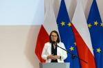 minister finansów Magdalena Rzeczkowska przemawia, za nią flagi Polski i Unii Europejskiej
