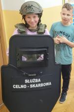 Dziewczynka przymierza wyposażenie funkcjonariusza Służby Celno-Skarbowej