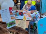 Stoisko promocyjne podlaskiej KAS, dzieci przy stoliku kolorujące obrazki