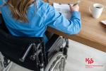 kobieta na wózku inwalidzkim przy biurku wypełnia dokumenty Obraz autorstwa freepik