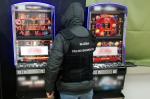 Funkcjonariusz KAS stoi przed dwoma automatami do gier hazardowych