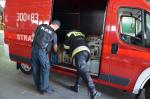 Funkcjonariusz KAS i strażak ładują alkohol do samochodu strażackiego